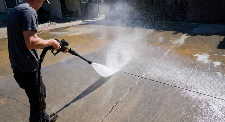 Contractor pressure-washing a concrete driveway